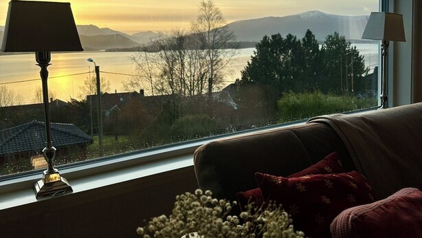 Ein Zimmer mit Blick auf einen See und Berge, eine Couch und zwei Lampen.