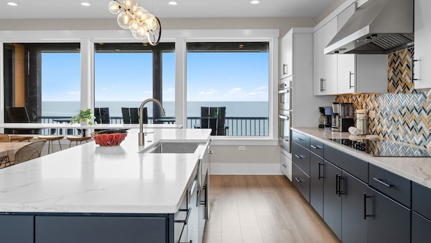 Cozinha moderna com uma ilha grande, vista para o mar e backsplash com padrão herringbone.
