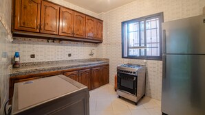 A kitchen with wooden cabinets, a stainless steel refrigerator, a gas stove, and a window.