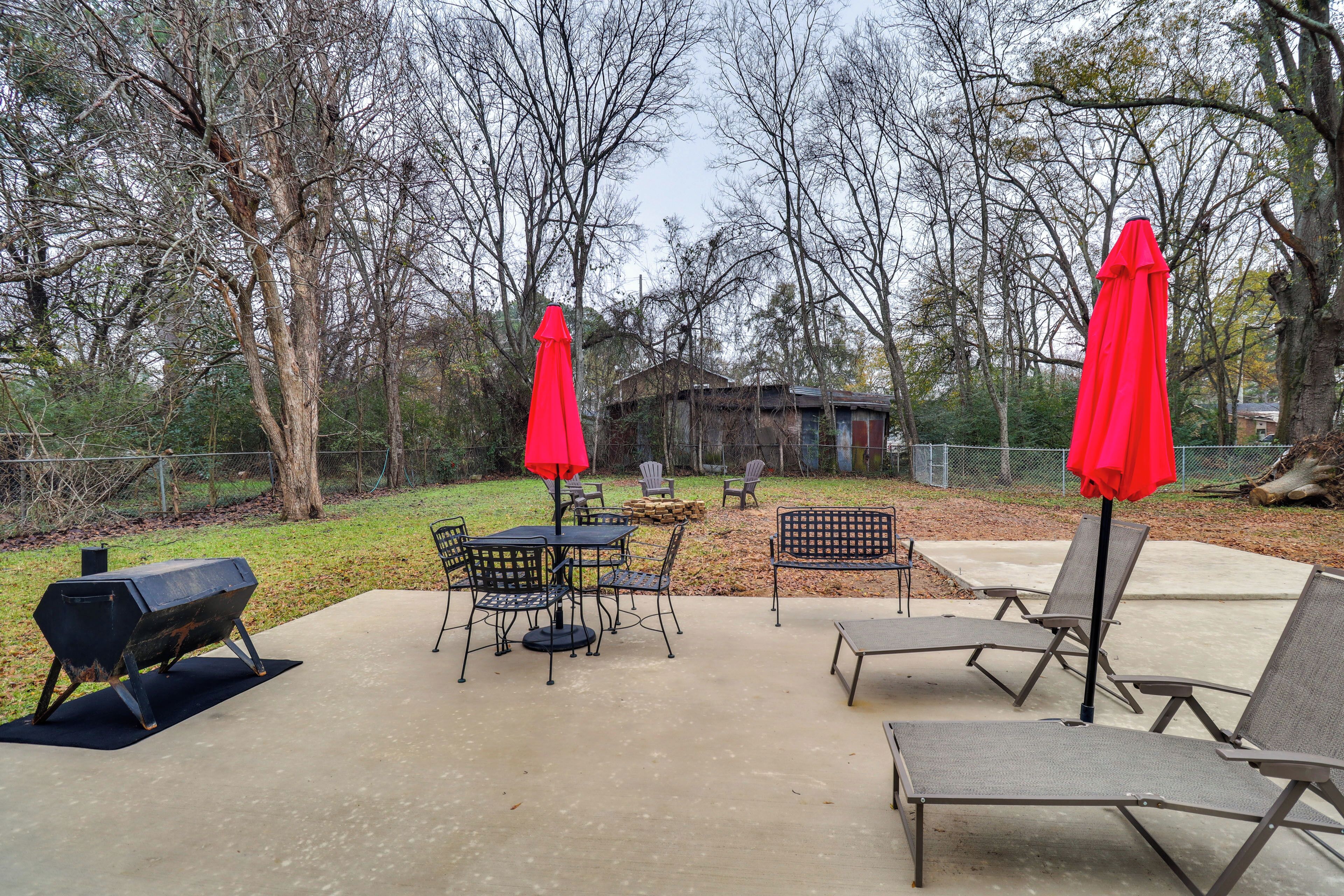 An outdoor patio area with a barbecue grill, dining table with chairs, and lounge chairs.