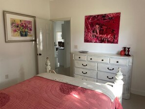 A bedroom with a bed, a dresser, a painting, and a mirror. - The ArtHouse - modern, stylishly furnished vacation home with pool! (Lehigh Acres)