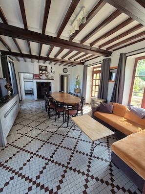 A dining area with a wooden table and chairs, a sofa, and a tiled floor.