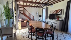Ein Essbereich mit Holztisch und Stühlen, Fliesenboden und einer Treppe zu einem anderen Raum.