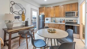 Una cocina moderna con armarios de madera, electrodomésticos de acero inoxidable y una mesa de comedor redonda con sillas.