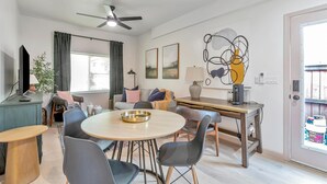 Una sala de estar moderna con una mesa redonda de comedor, un sofá, un televisor y un ventilador de techo.