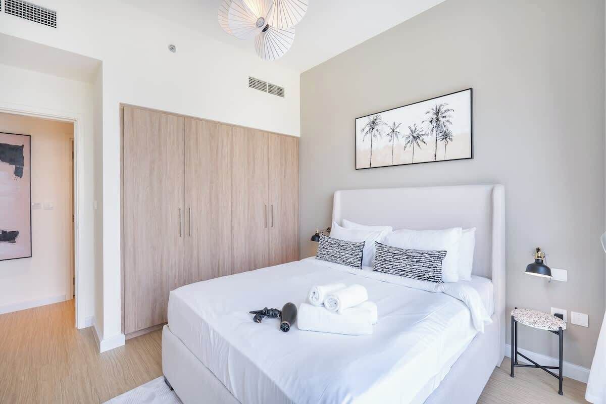 A modern bedroom with a large bed, a wardrobe, and a framed picture on the wall.