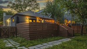 A house with a wooden fence, a staircase leading to a deck, and string lights. - Hot Tub | Fully-Fenced Yard |The Bubbly Suite (Atlanta)