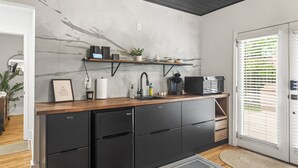 A modern kitchen with a marble backsplash, black appliances, and a wooden countertop. - Hot Tub | Fully-Fenced Yard |The Bubbly Suite (Atlanta)