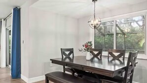 Een eethoek met een donker houten tafel, passende stoelen en een bank.