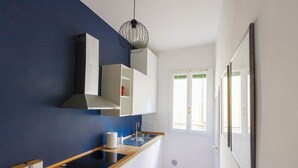 Une cuisine moderne avec un plan de travail noir, des armoires blanches et un mur d’accent bleu.