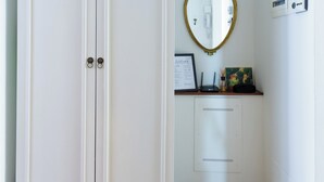 Une pièce avec une armoire blanche, un miroir, un petit bureau avec un ordinateur portable et un panneau d’accueil encadré.