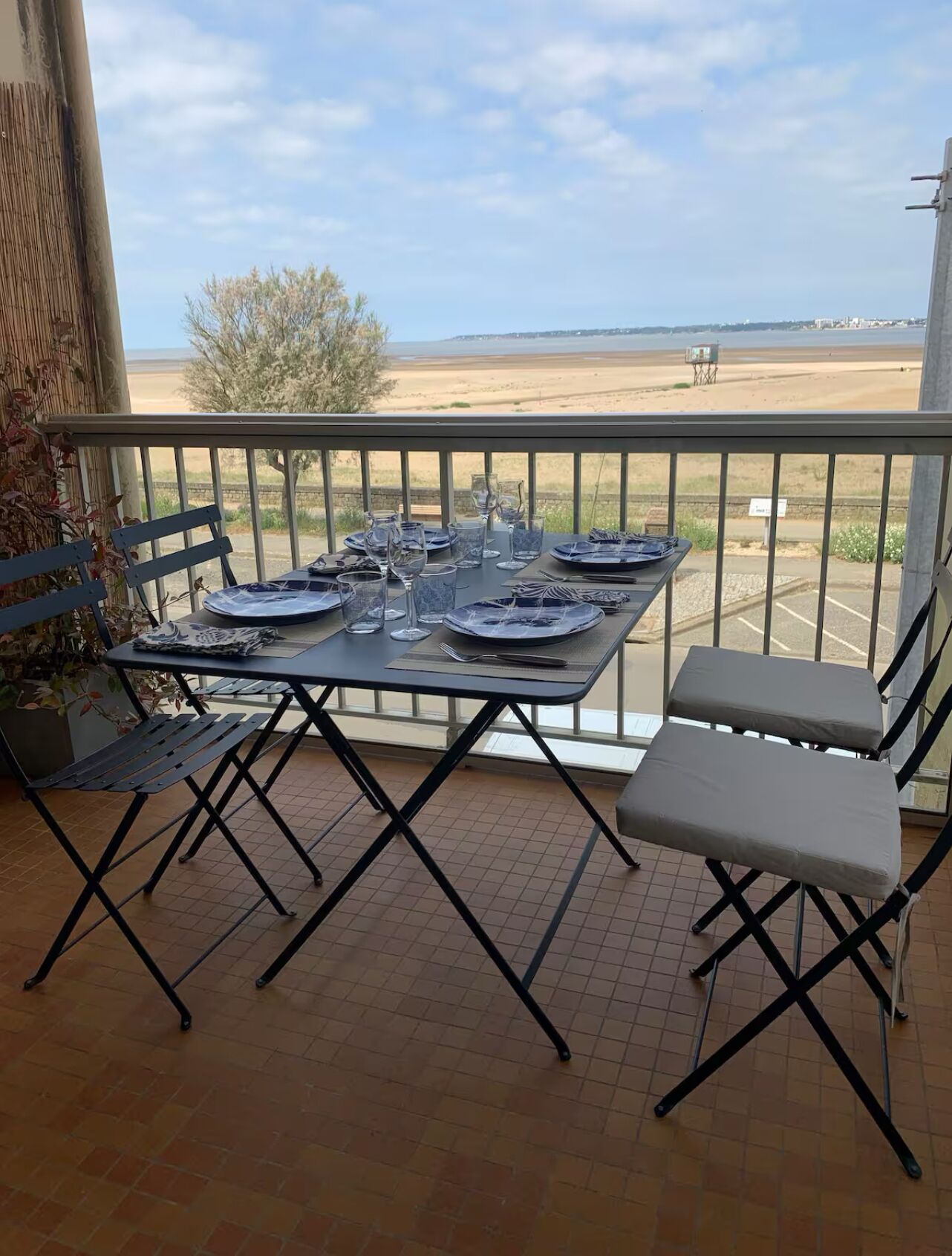 Een balkon met een eettafel, met uitzicht op een strand.