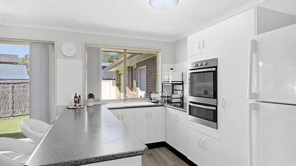 Una cocina moderna con una isla grande, horno integrado y vistas al patio trasero.