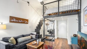 A modern living room with a black leather sofa, a wooden coffee table, and a colorful rug. - Tomboy Lodge 144 1 Bedroom Condo (Telluride)