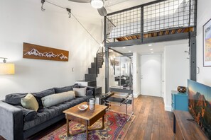 A modern living room with a black leather sofa, a wooden coffee table, and a colorful rug. - Tomboy Lodge 144 1 Bedroom Condo (Telluride)