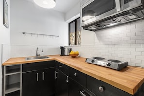 A modern kitchen with a wooden countertop, stainless steel appliances, and a window with a view.