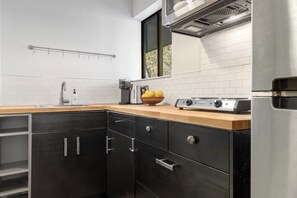 Una cocina moderna con un refrigerador de acero inoxidable, una encimera de madera y un armario negro con cajones.