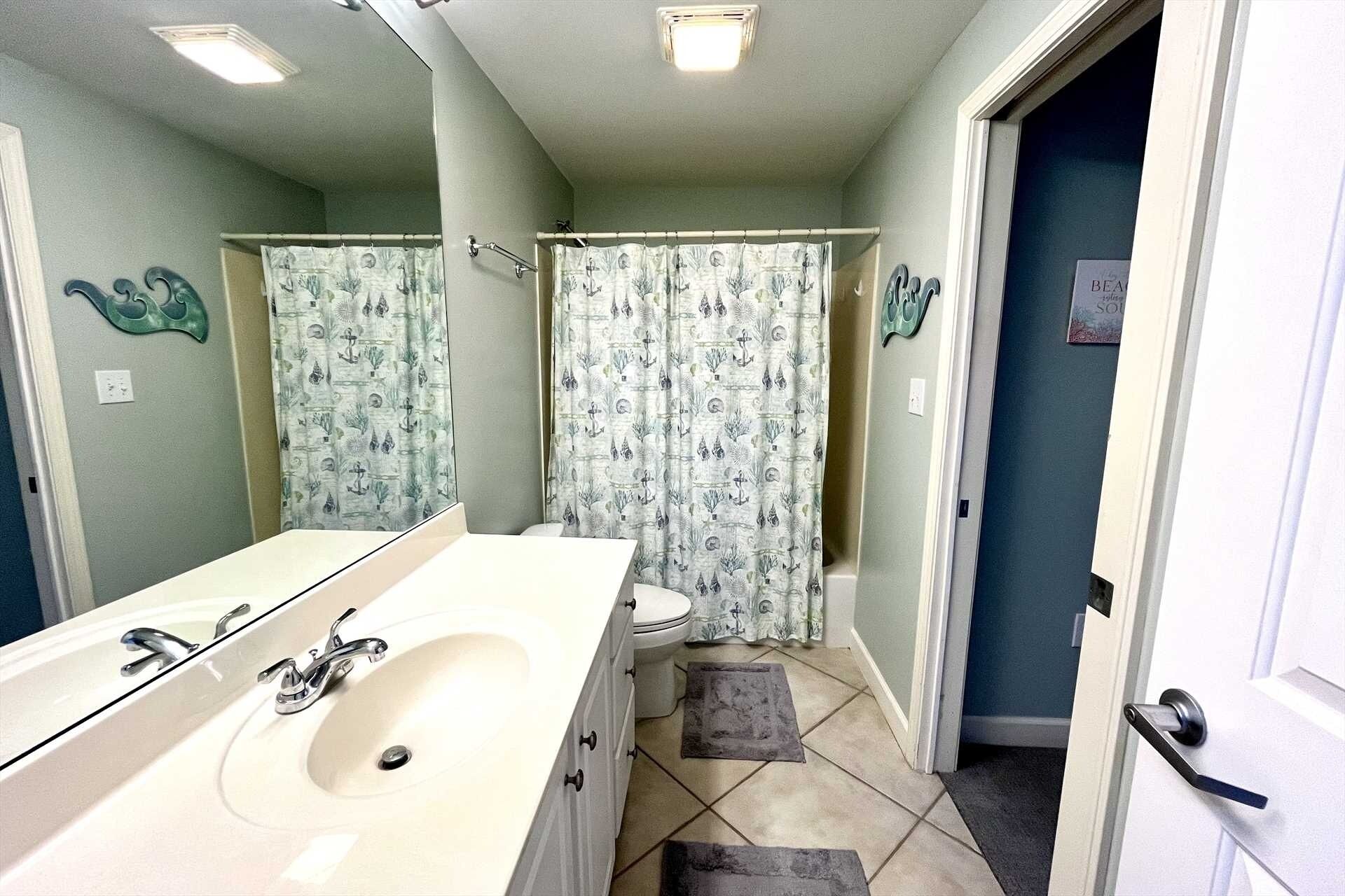 Une salle de bain avec un grand lavabo, des toilettes et un rideau de douche.