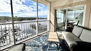 Un balcón con vistas a un lago y un muelle, un sofá y una mesa.