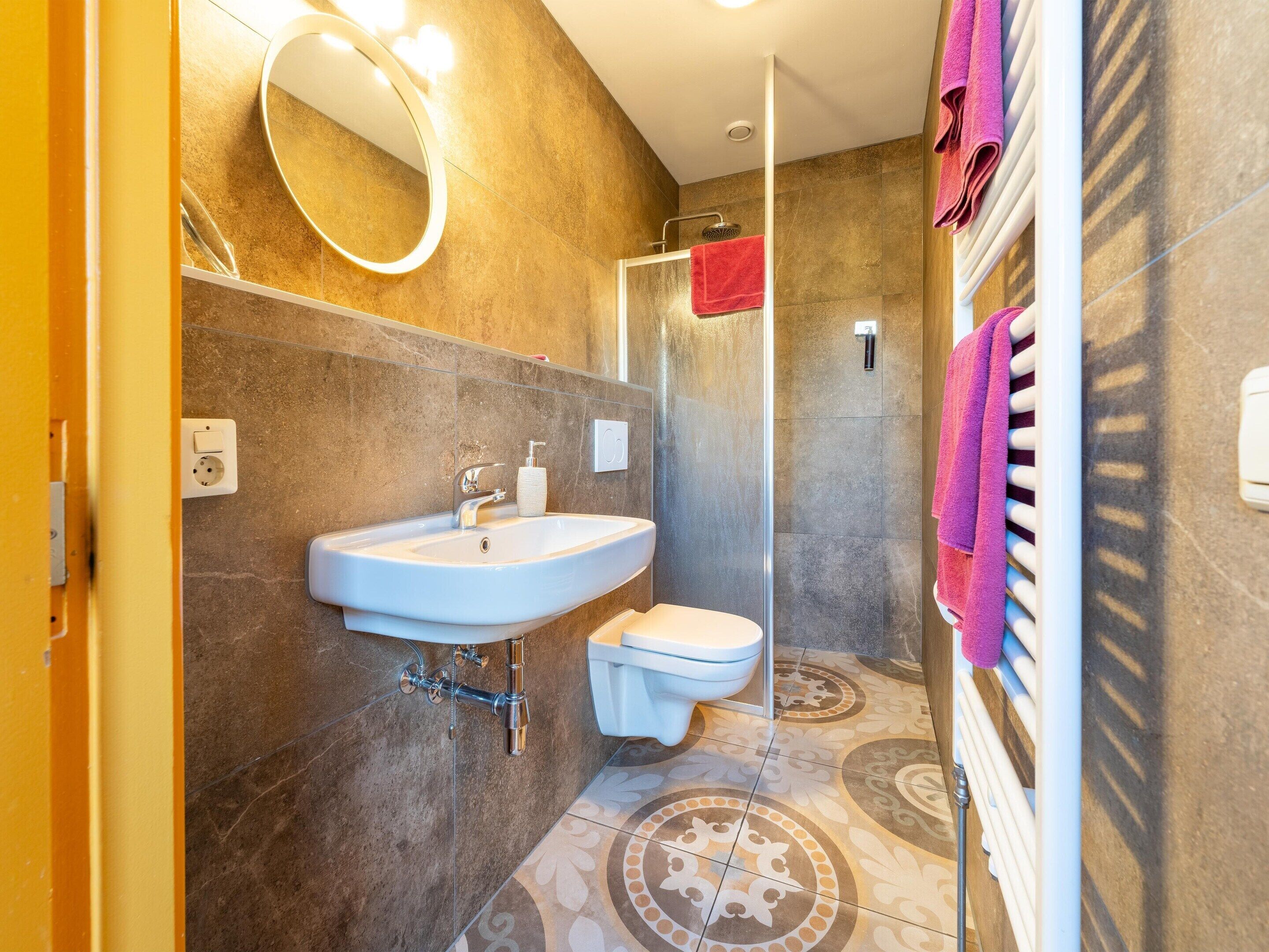 Een badkamer met een wastafel, toilet en douche.