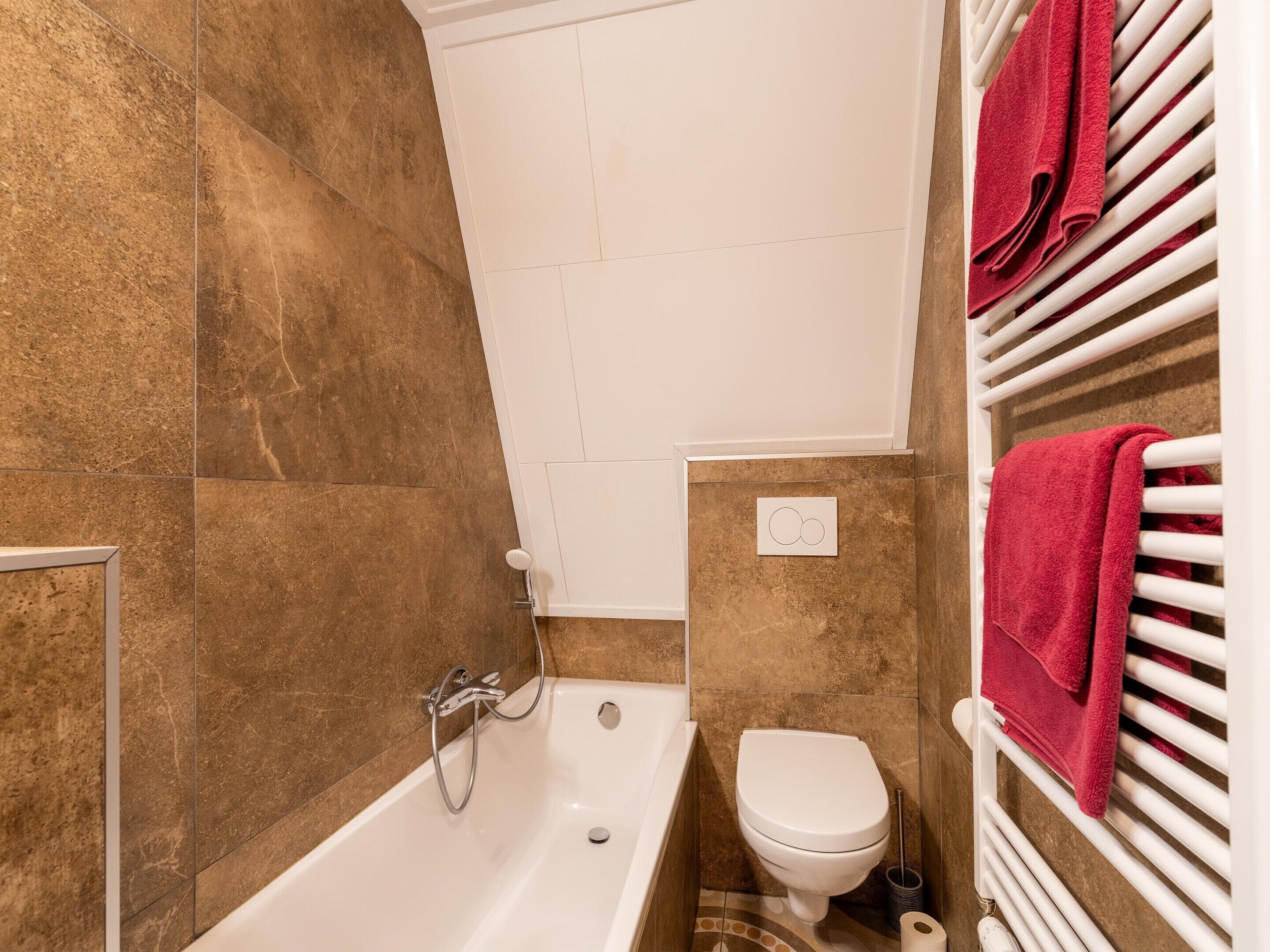 Une salle de bain avec une baignoire, des toilettes et un porte-serviettes.