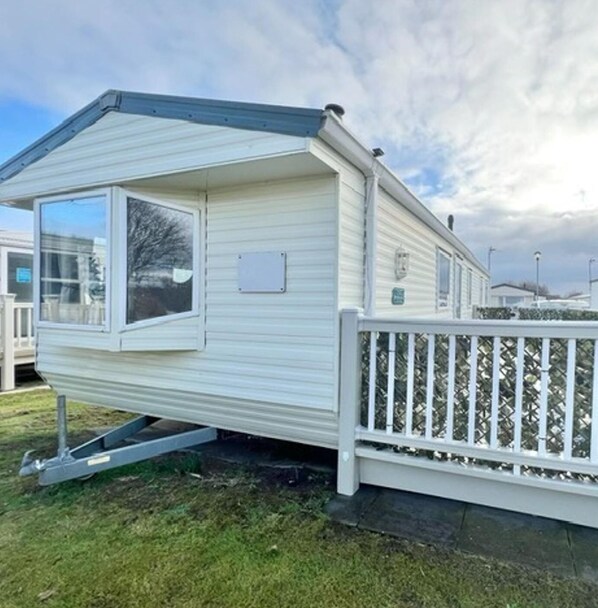 A mobile home with a large window, a white fence, and a grassy yard. - 3 Bed-7 Berth-mablethorpe-wifi-pet Friendly (Mablethorpe)