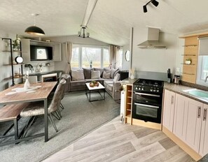 Une cuisine compacte équipée d’une cuisinière, d’un four et d’un évier, jouxtant un coin repas avec une table et des chaises.