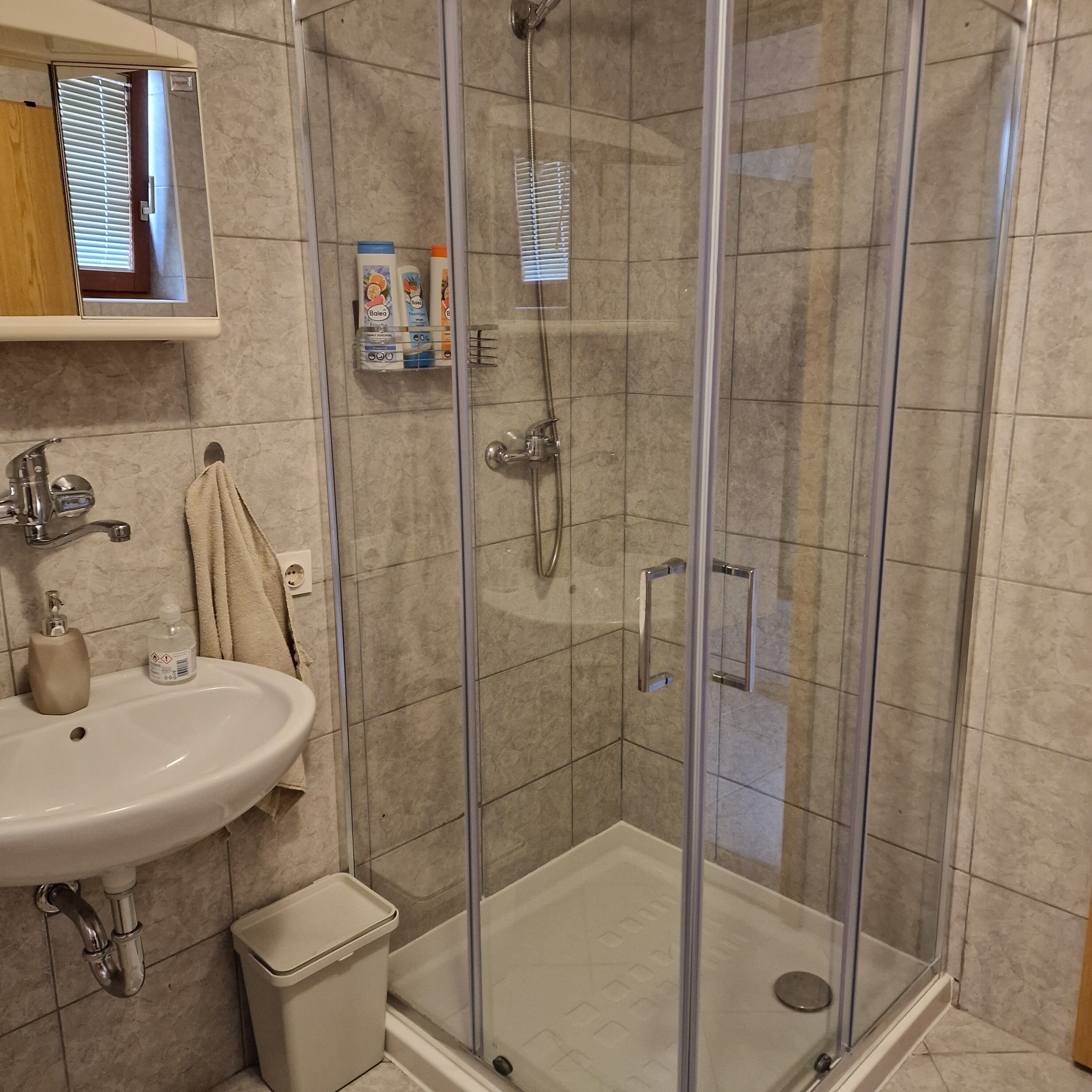 Une salle de bain avec une douche à parois de verre, un lavabo et des articles de toilette.