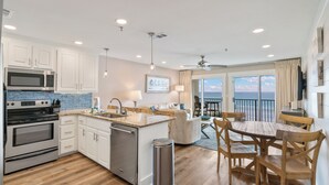 Una cocina moderna con armarios blancos, electrodomésticos de acero inoxidable y una mesa de comedor de madera con sillas.