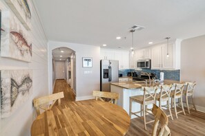 Une cuisine moderne avec des meubles blancs, une table à manger en bois et des tabourets de bar.