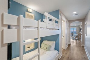 Une chambre avec des lits superposés, donnant sur le balcon et comprenant un coin repas.