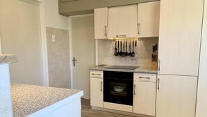 A compact kitchen with white cabinets, a built-in oven, and a countertop. - Bungalow in Sint Maartenszee With Veranda (Sint Maartensvlotbrug)