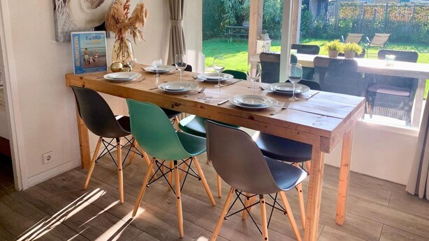 A dining area with a wooden table set for four, surrounded by modern chairs. - Bungalow in Sint Maartenszee With Veranda (Sint Maartensvlotbrug)