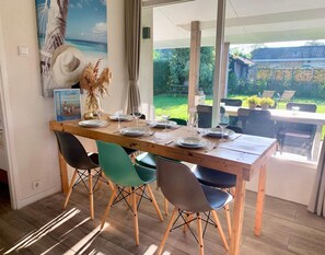 Un coin repas avec une table en bois dressée pour quatre personnes, entourée de chaises modernes.