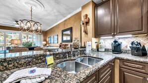 A kitchen with granite countertops, a double sink, and wooden cabinets. - Adagio D-103 Poolside 3/3 - NEW to program for 2025! (Santa Rosa Beach)