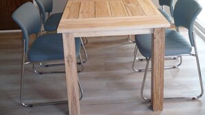 A dining area with a wooden table, six chairs, and a chandelier. - Cosy Holiday Home Near Beach (Sint Maartensvlotbrug)