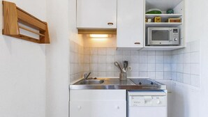 A compact kitchen with white cabinets, a stainless steel sink, a microwave, and a dishwasher.