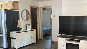 Ein modernes Wohnzimmer mit großem Flachbildfernseher, Backofen und Kühlschrank.