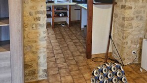 Una cucina rustica con pareti in pietra a vista, travi in legno e pavimento piastrellato.