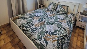 Una camera da letto con un letto, un comodino, una lampada, un quadro e una finestra con tende.