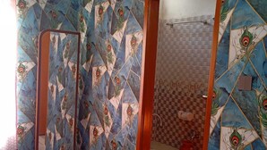 A bathroom with a peacock-themed tile backsplash, a wooden cabinet, and a mirror with a wooden frame. - Hotel Moon International  (Dhaka)