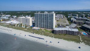 A coastal hotel with multiple buildings, a beach, and a clear sky. - ASHWORTH OCEAN FRONT (NORTH MYRTLE BEACH)