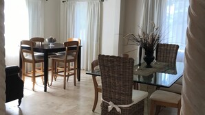 A dining area with a glass table, wicker chairs, and a ceiling fan.