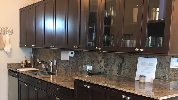 A kitchen with dark wooden cabinets, a granite countertop, and a built-in dishwasher.