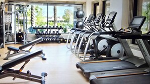 Un gimnasio con cintas de correr, máquinas de pesas y mancuernas.
