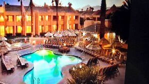 Un hotel con una amplia piscina al aire libre, sillas de descanso y sombrillas.