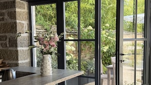 A modern kitchen with a stone wall, a built-in stove, and a large window overlooking a garden.