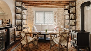 A rustic interior with exposed wooden beams, a stone wall, and a cozy seating area with a fireplace.