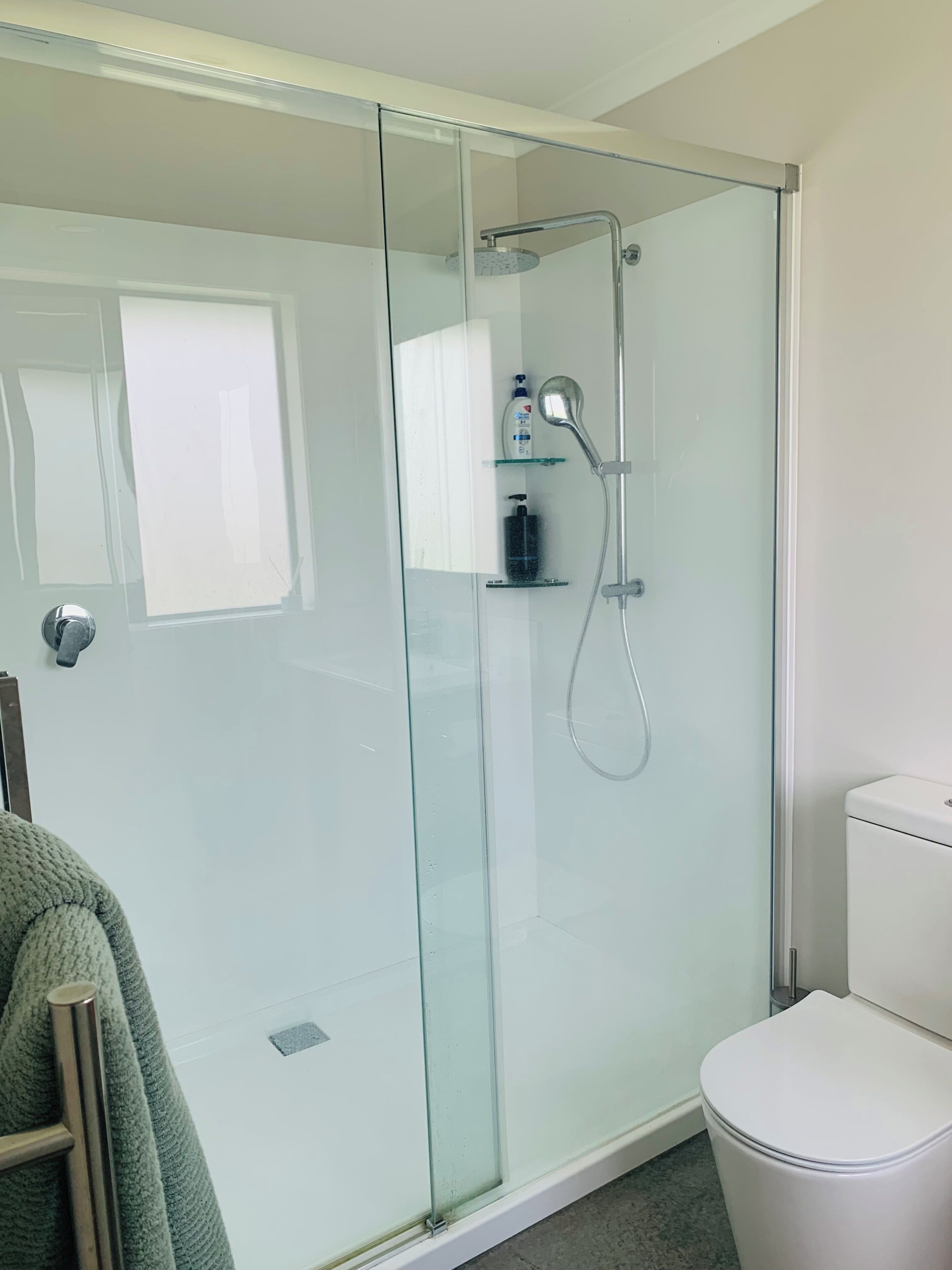 Ein modernes Badezimmer mit einer Duschkabine, einer Toilette und einem Handtuchhalter.