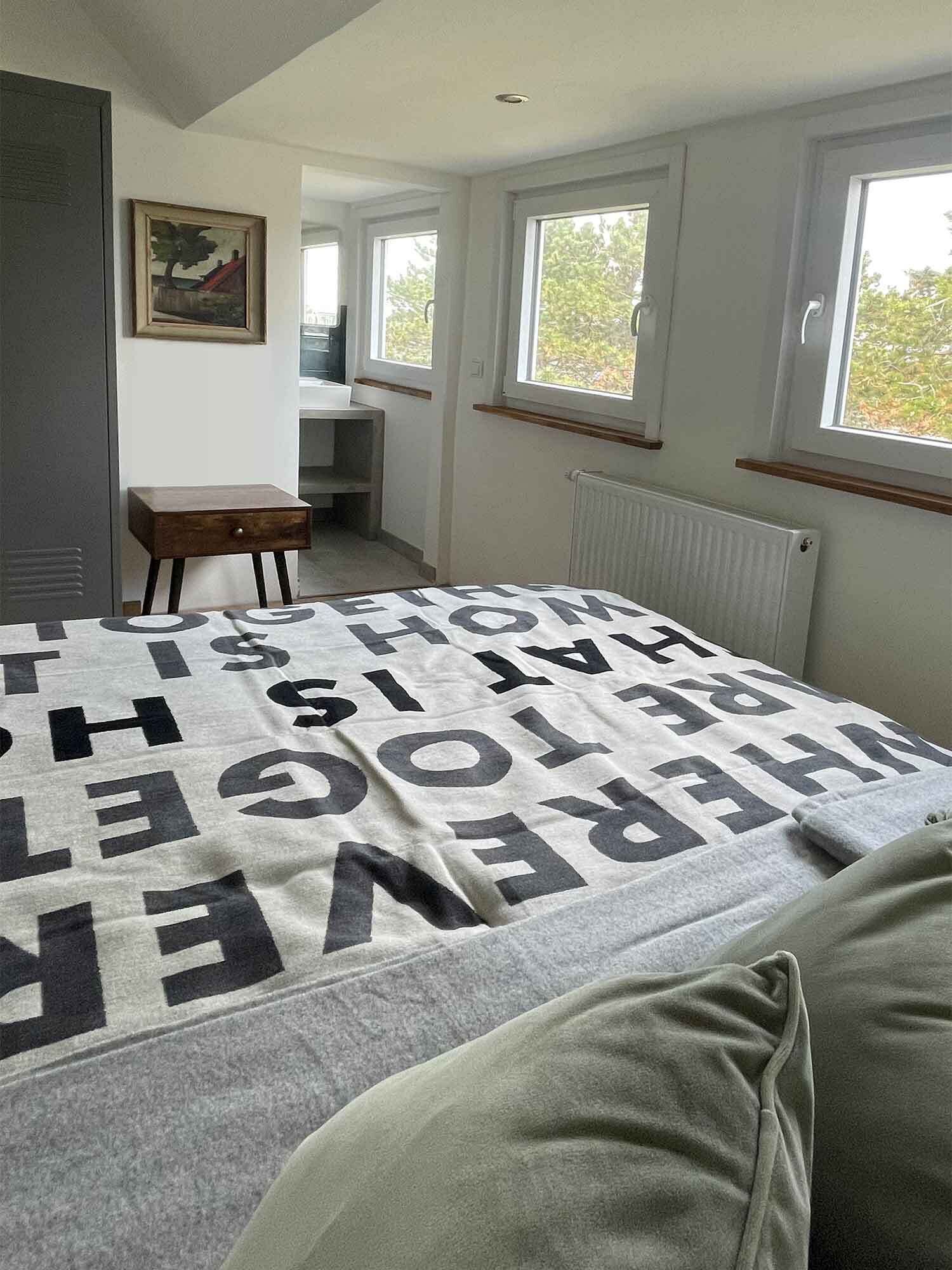 A bedroom with a bed, a desk, and a window.